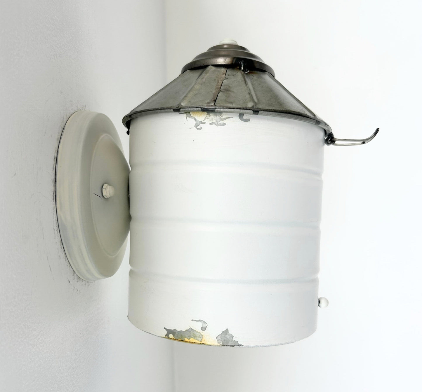 Wall-mounted light fixture with white glass shade and metal top on a white background
