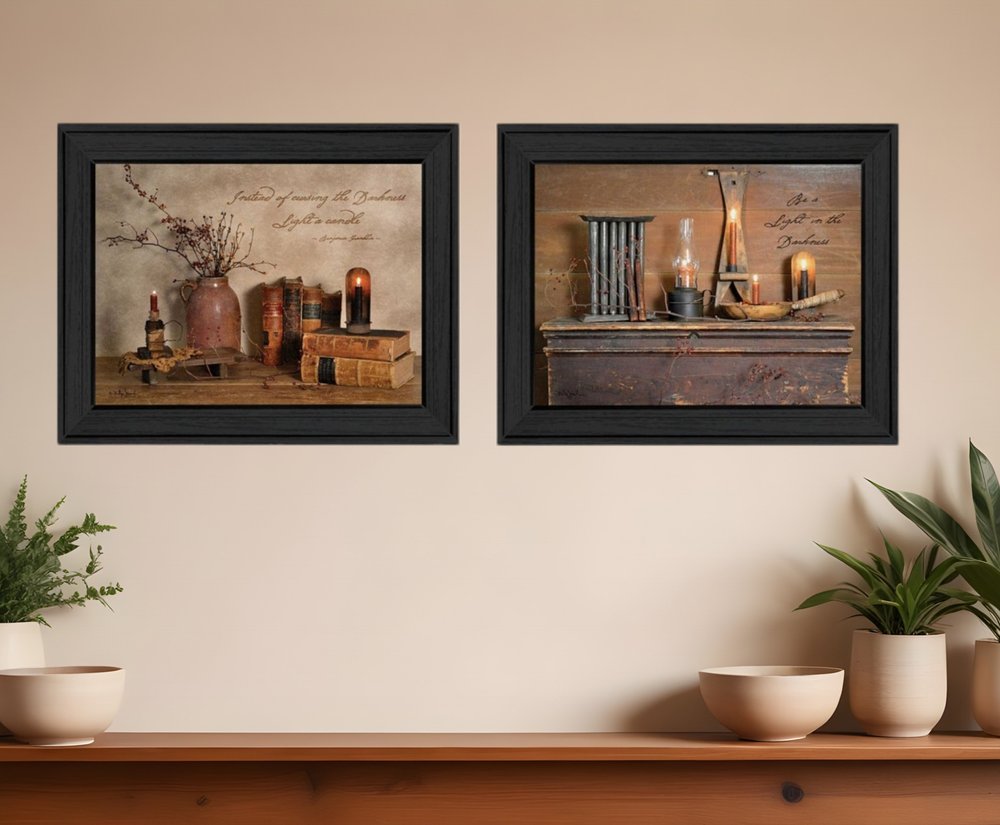 Two framed pictures on a wall with decorative elements and plants below.
