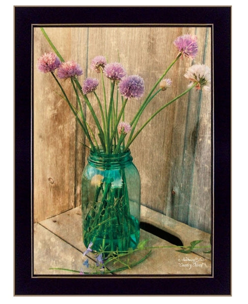 Green glass jar with purple flowers on a wooden surface, framed in black.