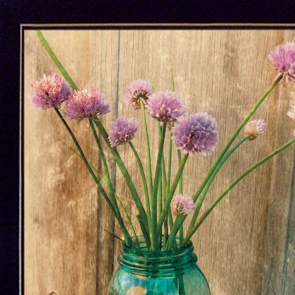 Purple flowers in a green jar against a wooden background