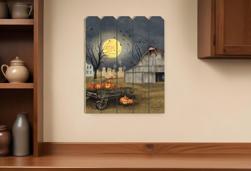 Decorative wall art of a farm scene with pumpkins and a moonlit sky on a wooden panel, displayed on a wall above a wooden shelf.