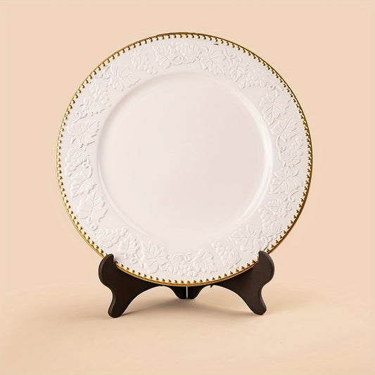 White plate with decorative gold rim on a stand against a beige background