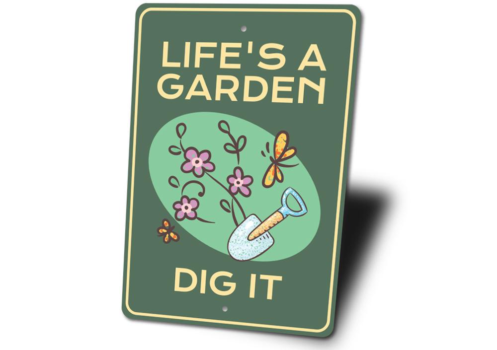 Sign with 'Life's a Garden, Dig It' text and gardening illustrations on a green background