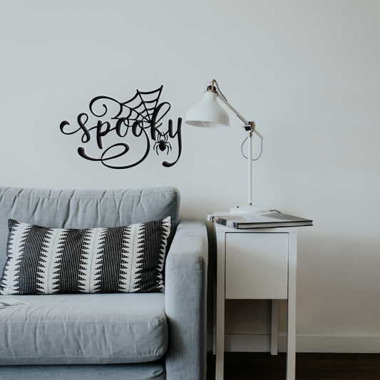 Living room with a 'Spooky' wall decal, gray sofa, and lamp.