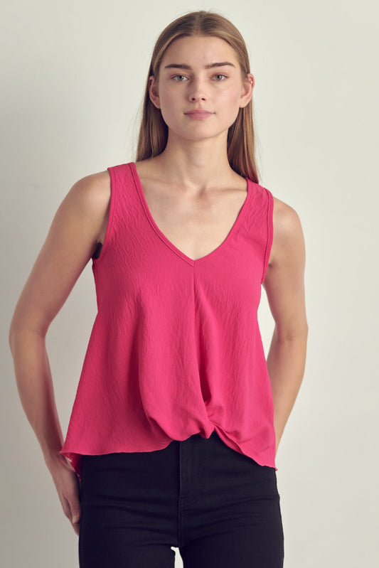 Woman wearing a bright pink sleeveless top against a plain background
