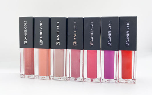 Set of Daniel Cole lip glosses in various colors on a white background