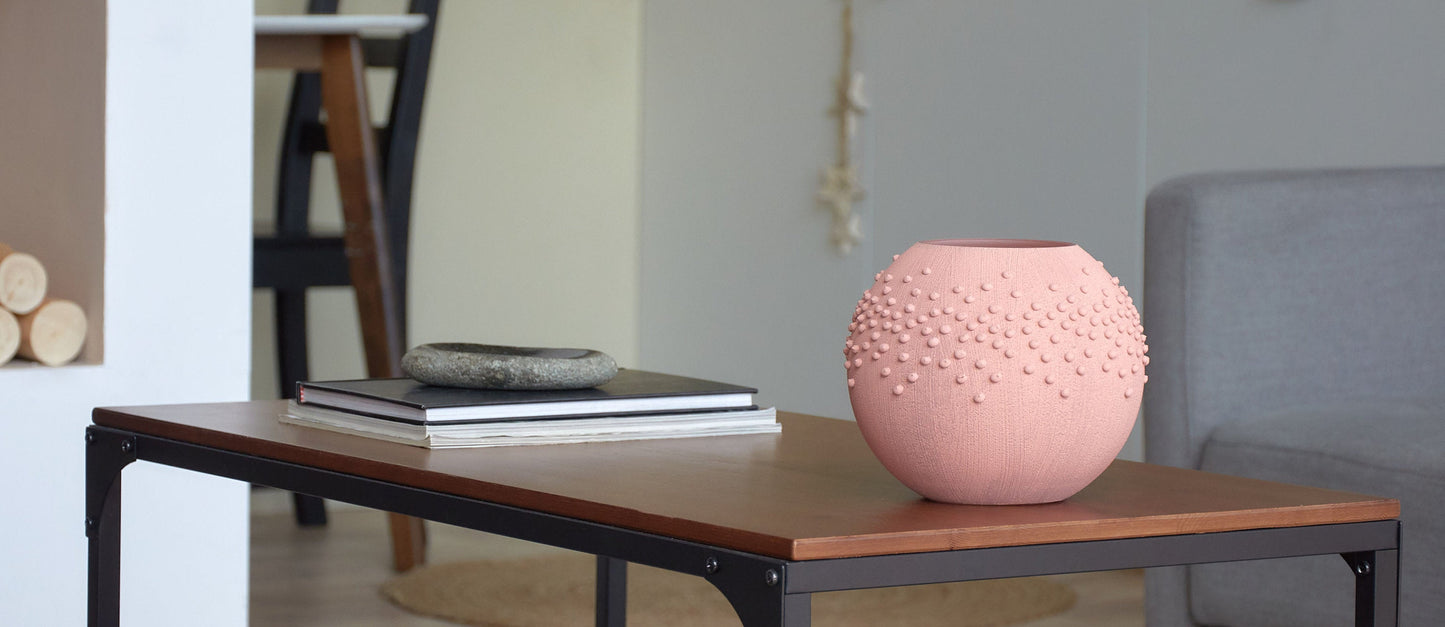 Pink textured vase on a wooden table in a living room setting