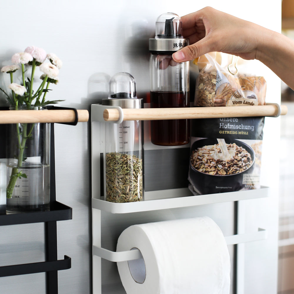 Kitchen shelf with spice containers, a roll of paper towels, and a small plant.