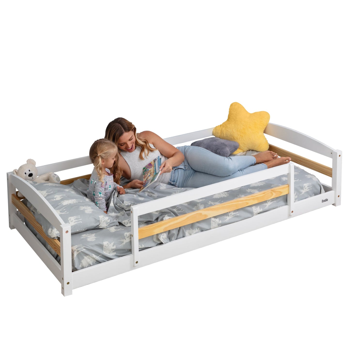 Woman and child on a white bed with wooden sides, reading a book.