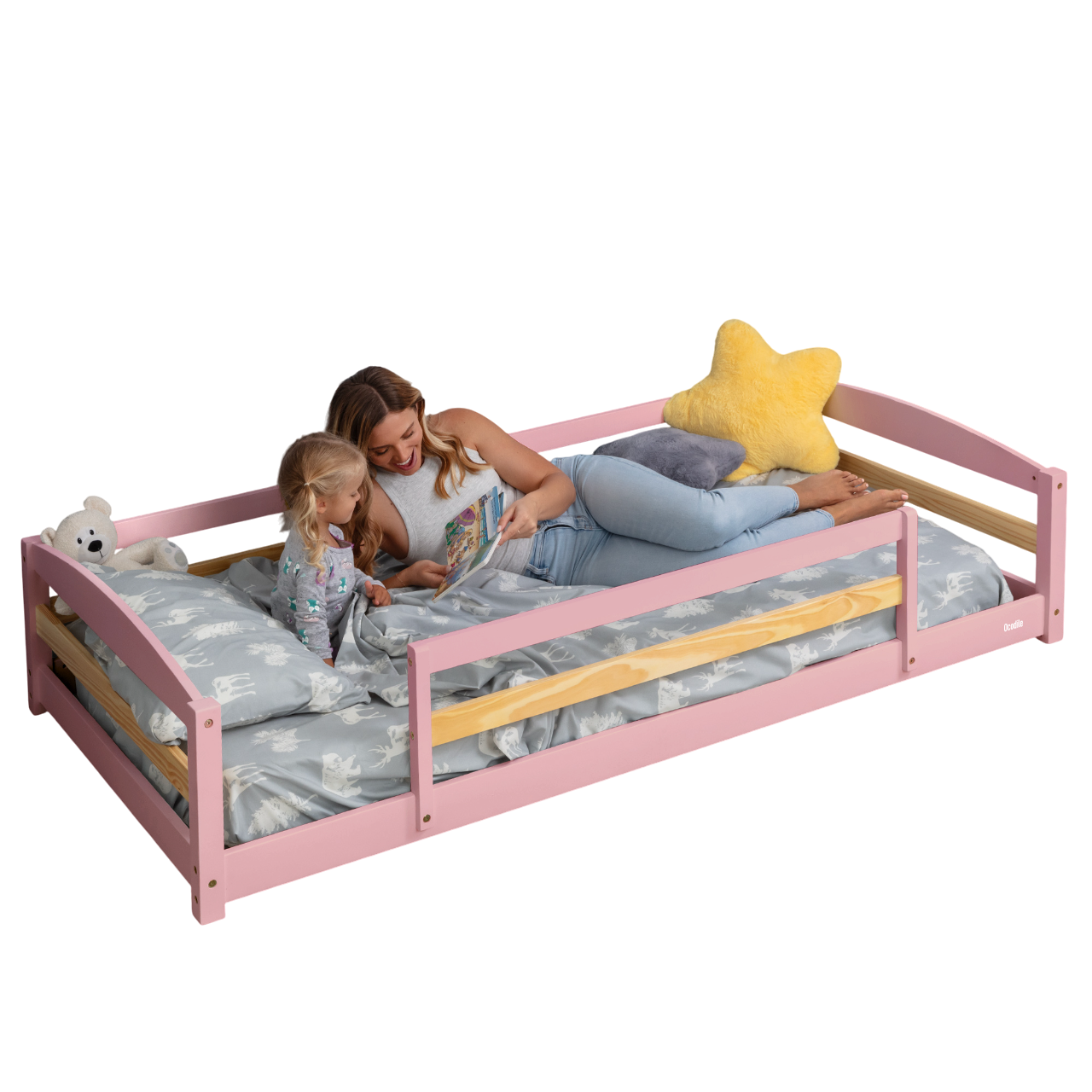 Woman and child on a pink bed with wooden sides, reading a book.