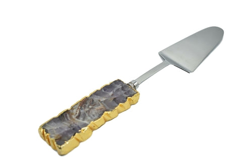 A set of three cake servers with gold trim handles and gemstone accents in amethyst, black quartz, and clear quartz.