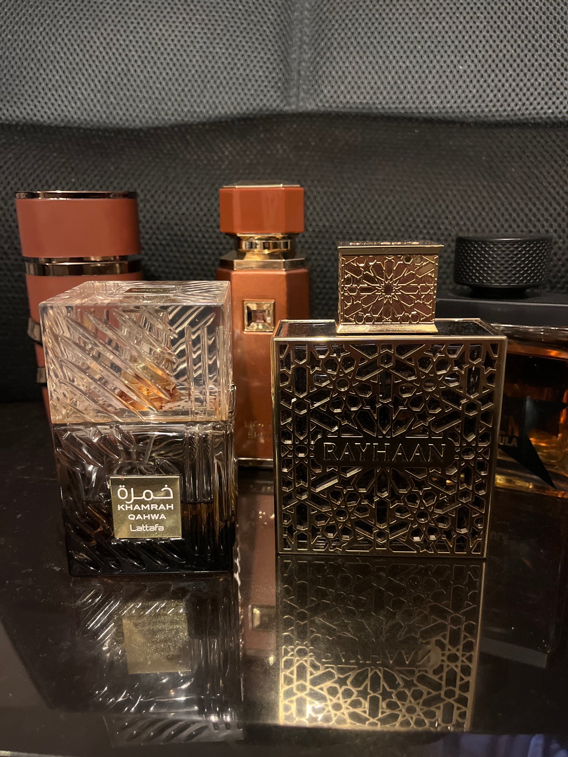 Perfume bottles with intricate designs on a reflective surface