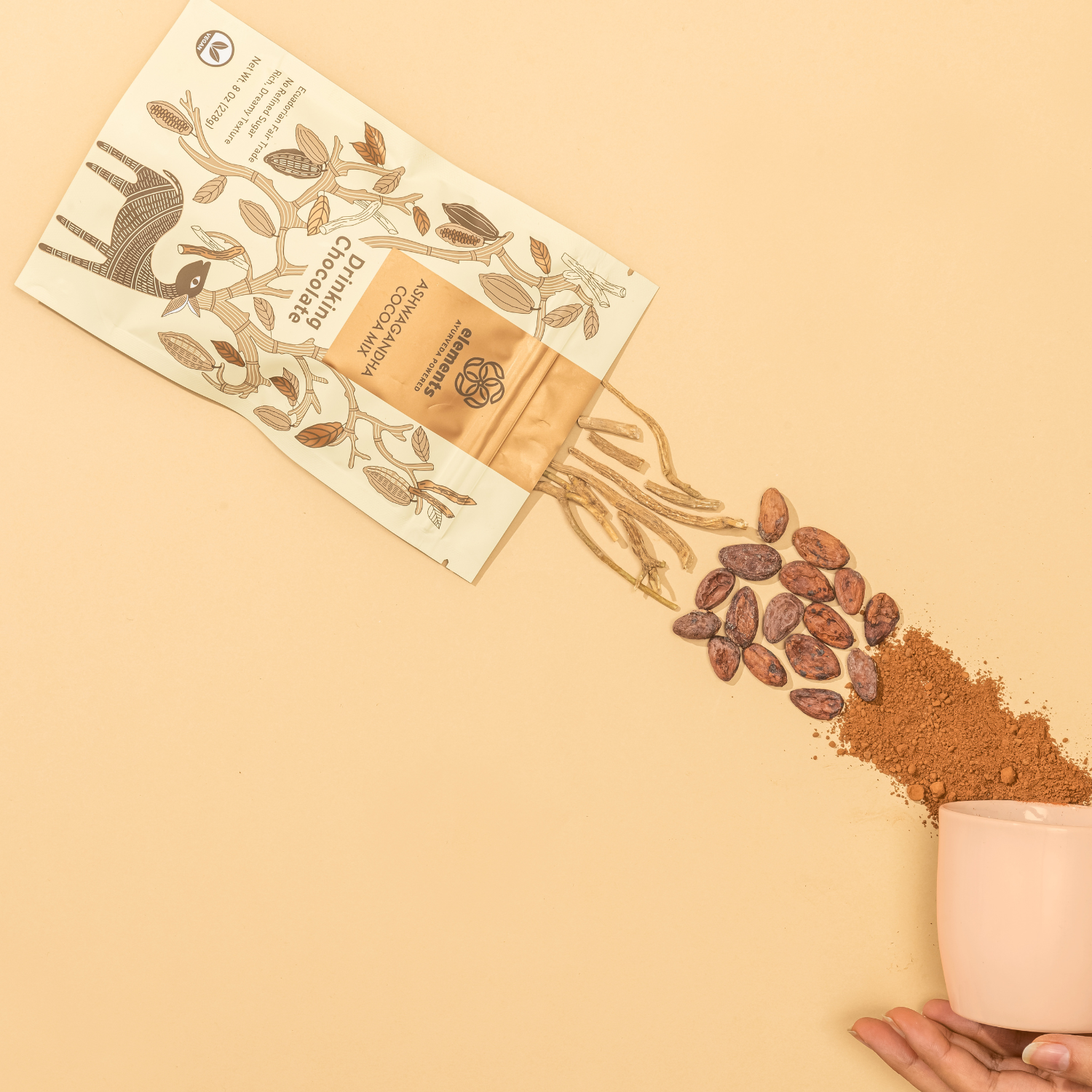 Cacao powder being poured from a small container onto a beige surface with a cacao bean packaging.