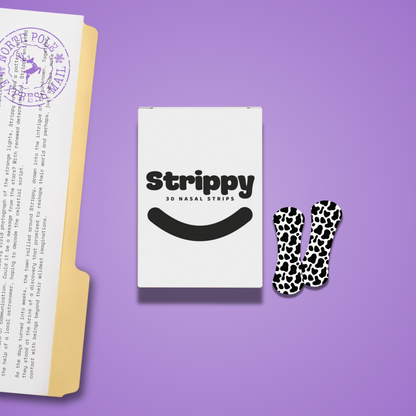 Pack of Strippy nasal strips on a purple background with a folded paper and decorative item.