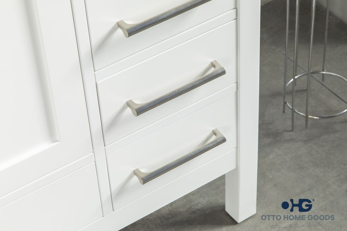 White bathroom vanity with silver handles on a gray floor.