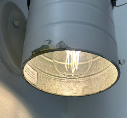 Light fixture with a visible bulb inside against a light blue background