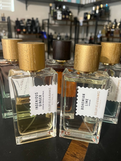 Four perfume bottles with gold caps and visible labels on a shelf.