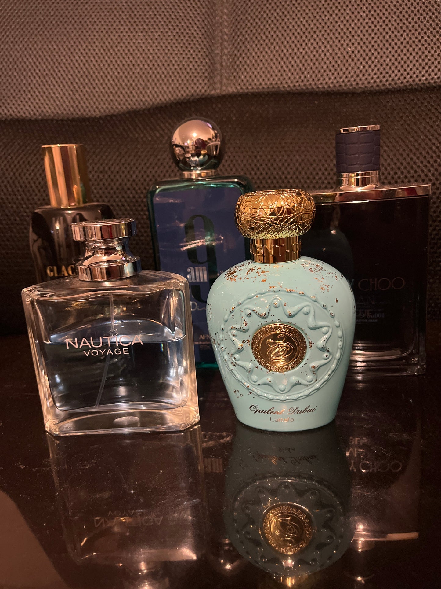 Collection of perfume bottles on a reflective surface with a textured background