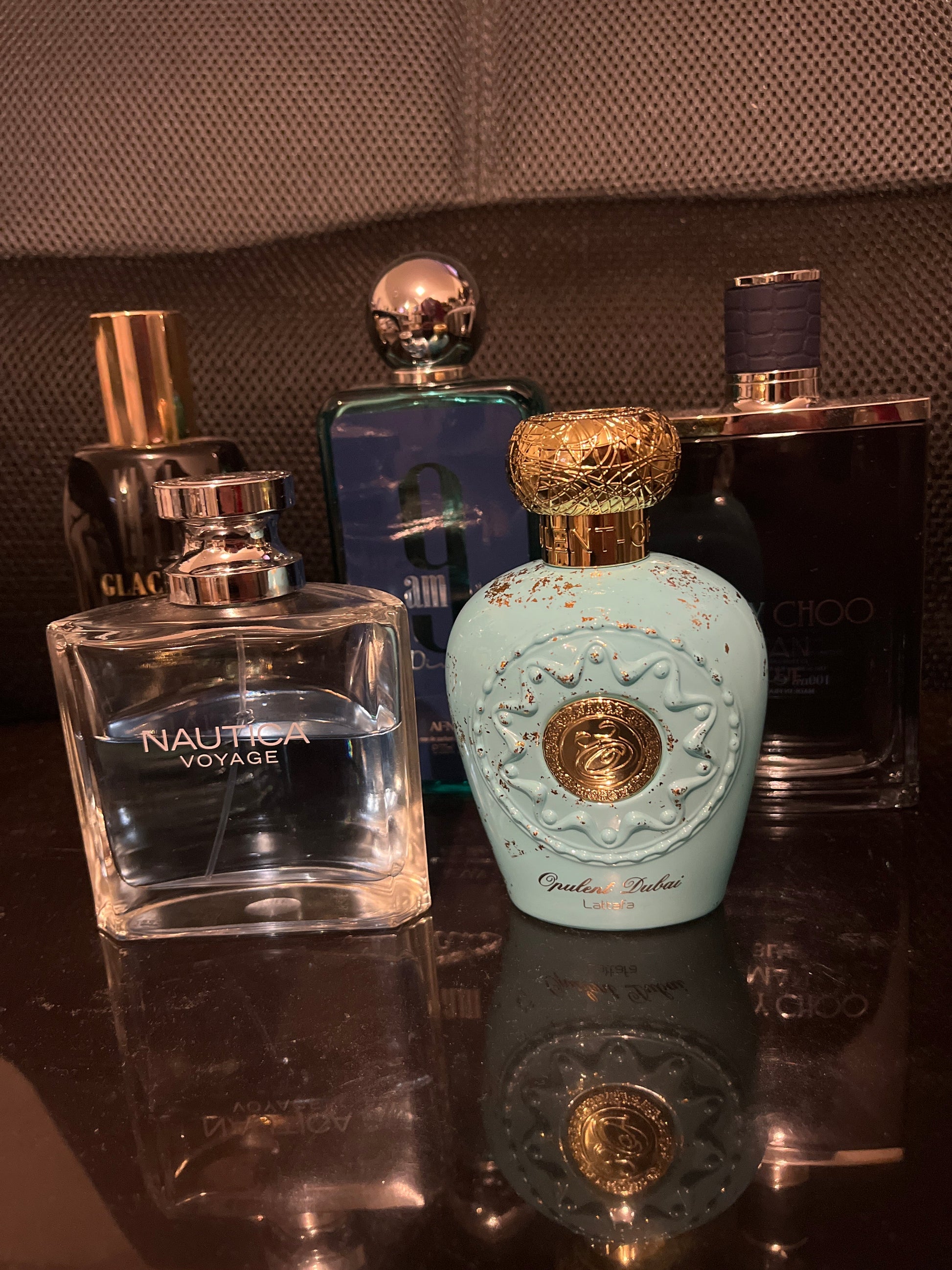 Collection of perfume bottles on a reflective surface with a textured background