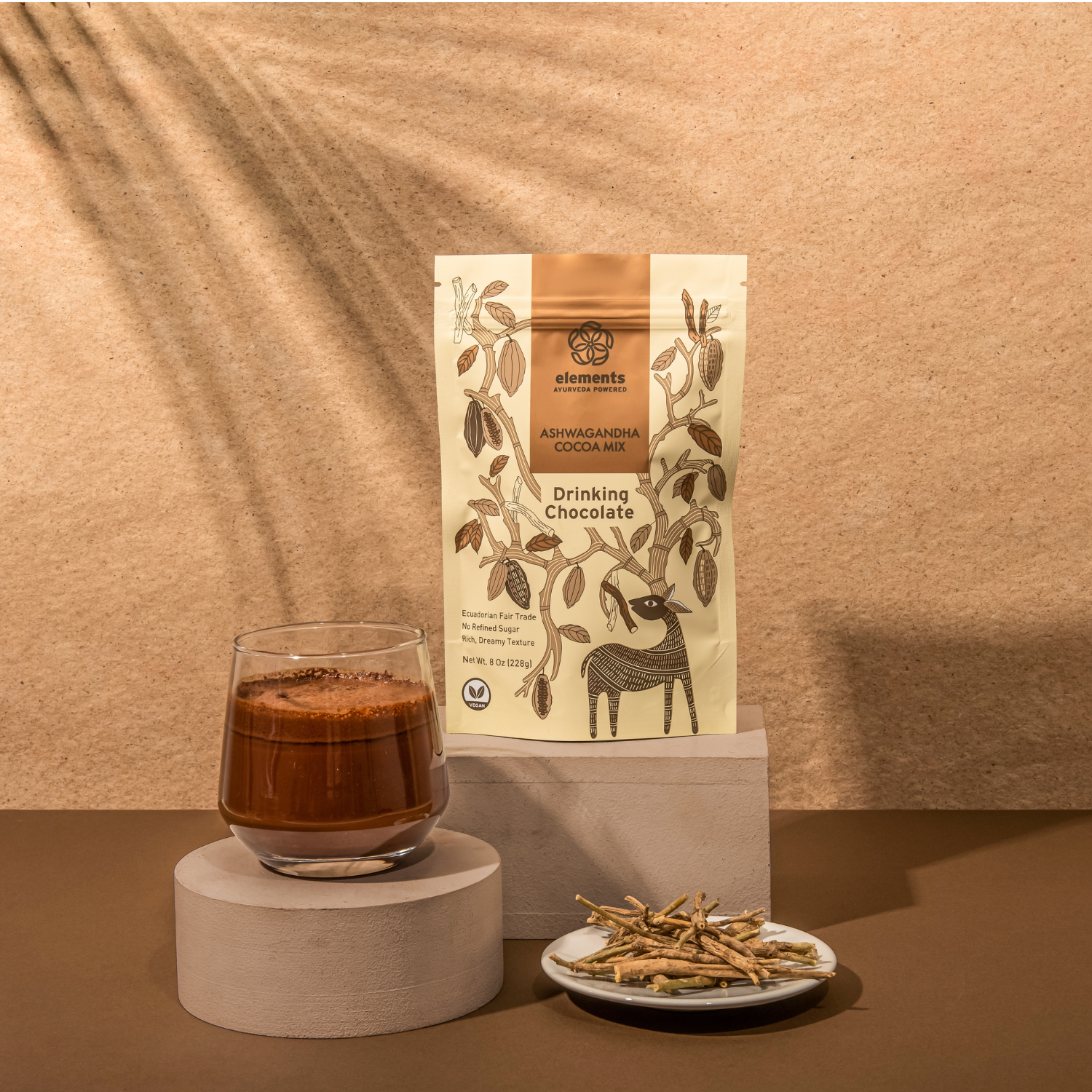 Glass of drinking chocolate with a package labeled 'elements' on a beige background