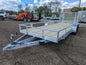 Silver utility trailer with wooden floor on a dirt lot with other trailers and equipment in the background.