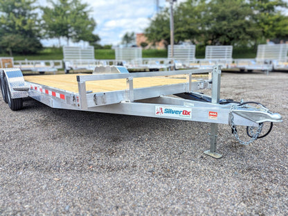 Silver Dx trailer on a paved surface with trees and buildings in the background