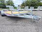 Silver Dx trailer on a paved surface with trees and buildings in the background
