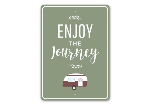 Green sign with 'Enjoy the Journey' text and a camper illustration on a white background
