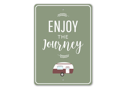 Green sign with 'Enjoy the Journey' text and a camper illustration on a white background