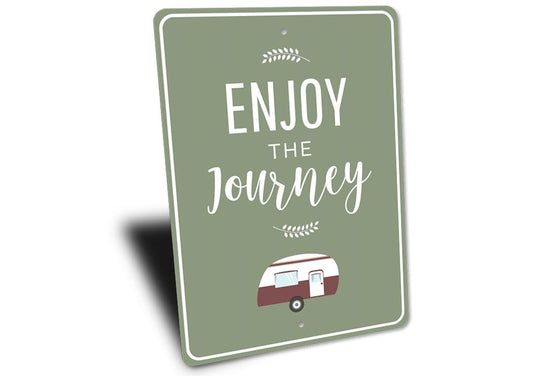 Green sign with 'Enjoy the Journey' text and a camper illustration on a white background