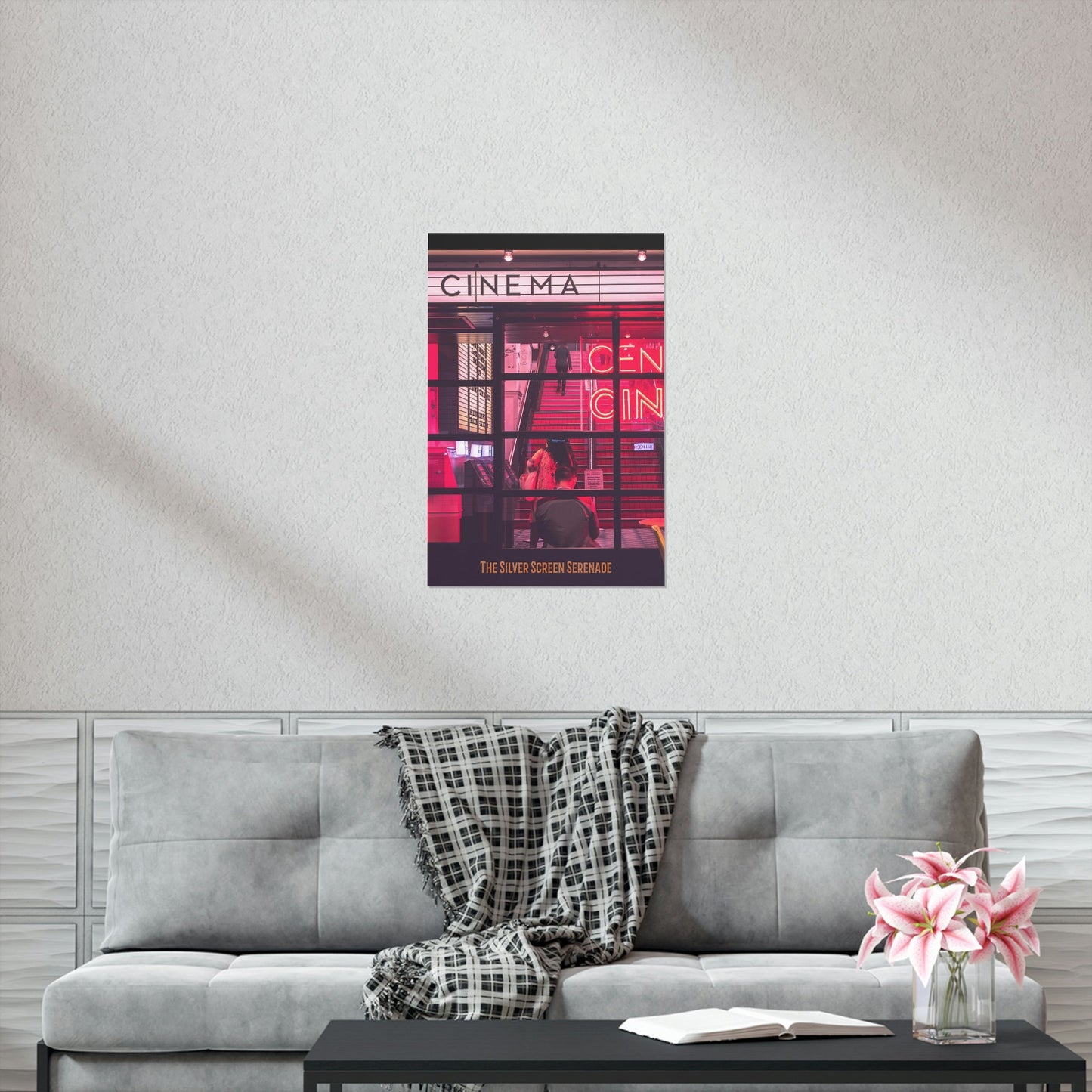 Poster of a cinema with people on a wall above a gray sofa with a blanket and flowers.