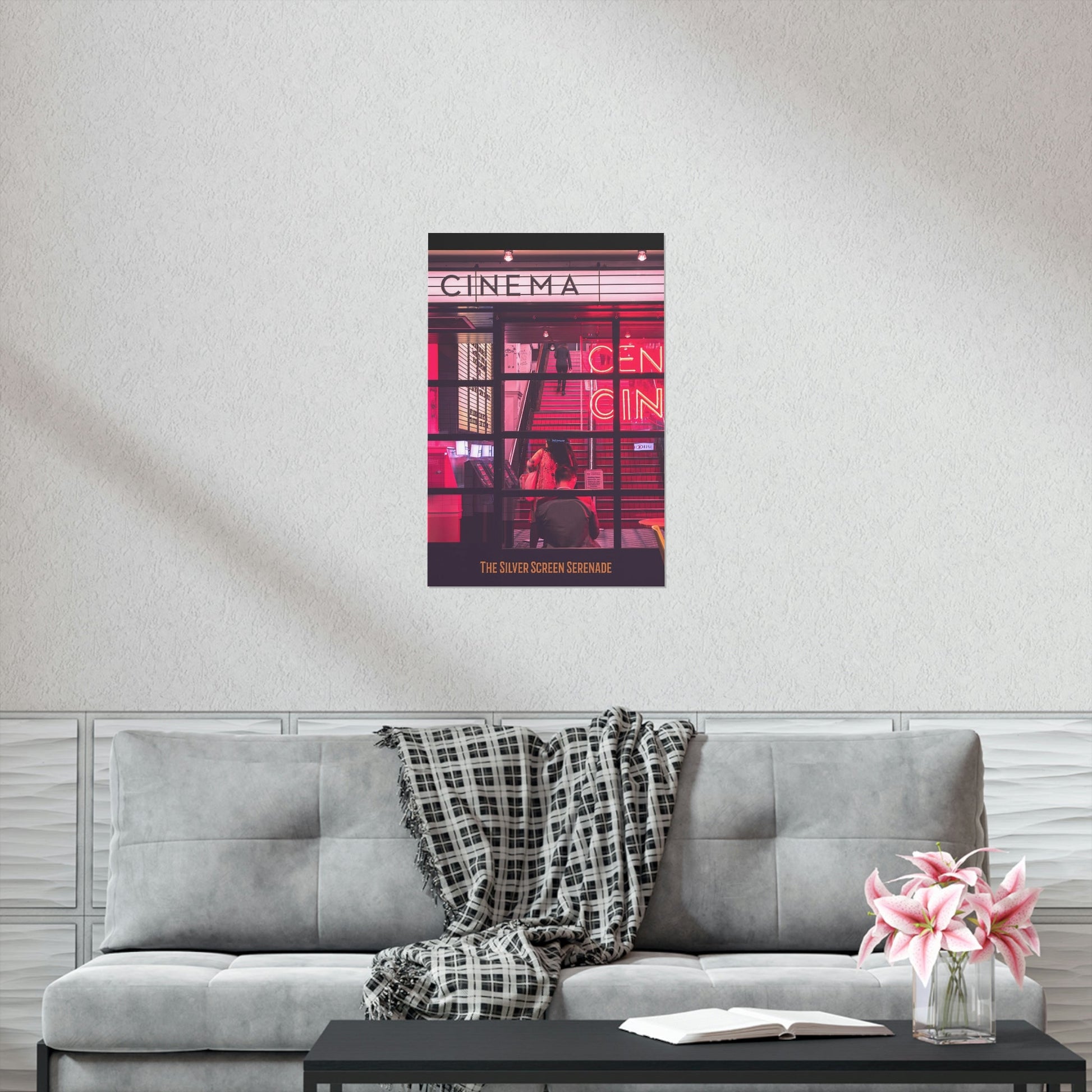 Poster of a cinema with people on a wall above a gray sofa with a blanket and flowers.