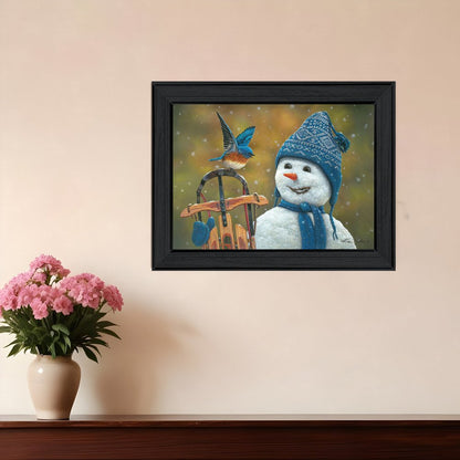 Framed artwork of a snowman with a bird on a swing against a beige wall.