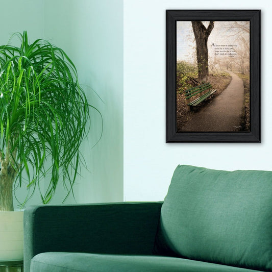 Framed artwork of a tree and bench on a wall above a green sofa with a plant.