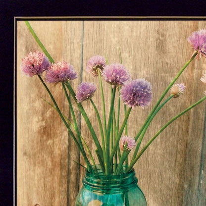 Purple flowers in a green jar against a wooden background