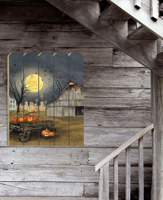 Wooden wall art depicting a barn, pumpkins, and a moonlit sky on a rustic wooden wall.