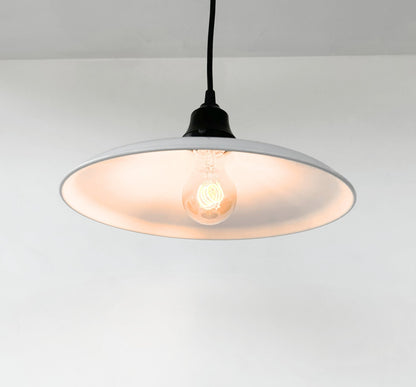 Pendant light with a white shade and black cord on a plain background