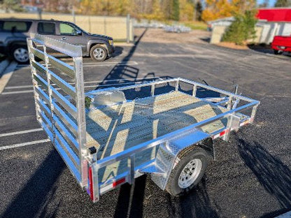 Metal utility trailer parked in a parking lot with a vehicle in the background