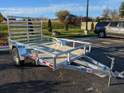 Metal utility trailer parked in a lot with a vehicle in the background