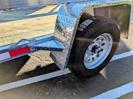 Close-up of a trailer wheel with diamond plate cover on a wet surface