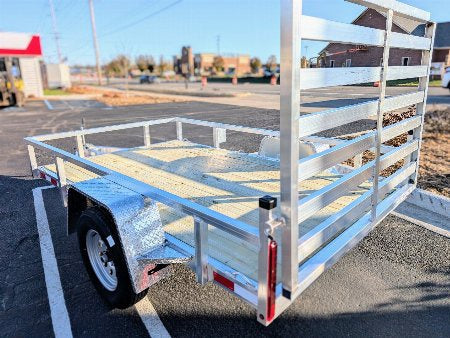 White utility trailer parked in a lot with buildings in the background
