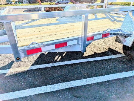 Metal trailer with a black mat on a paved surface
