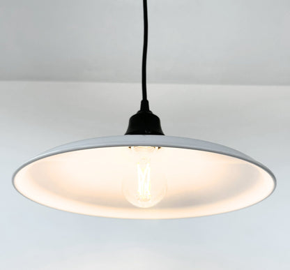 Pendant light with a white shade and black cord on a light gray background