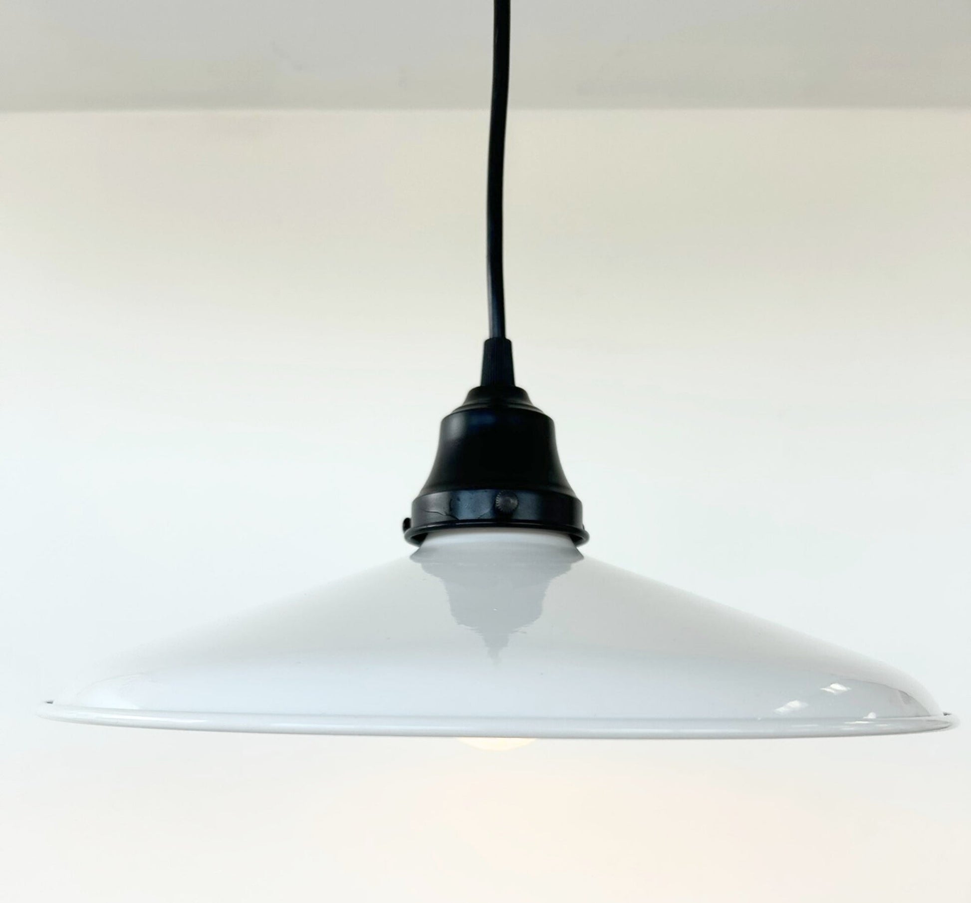 White pendant light with black fixture on a white background