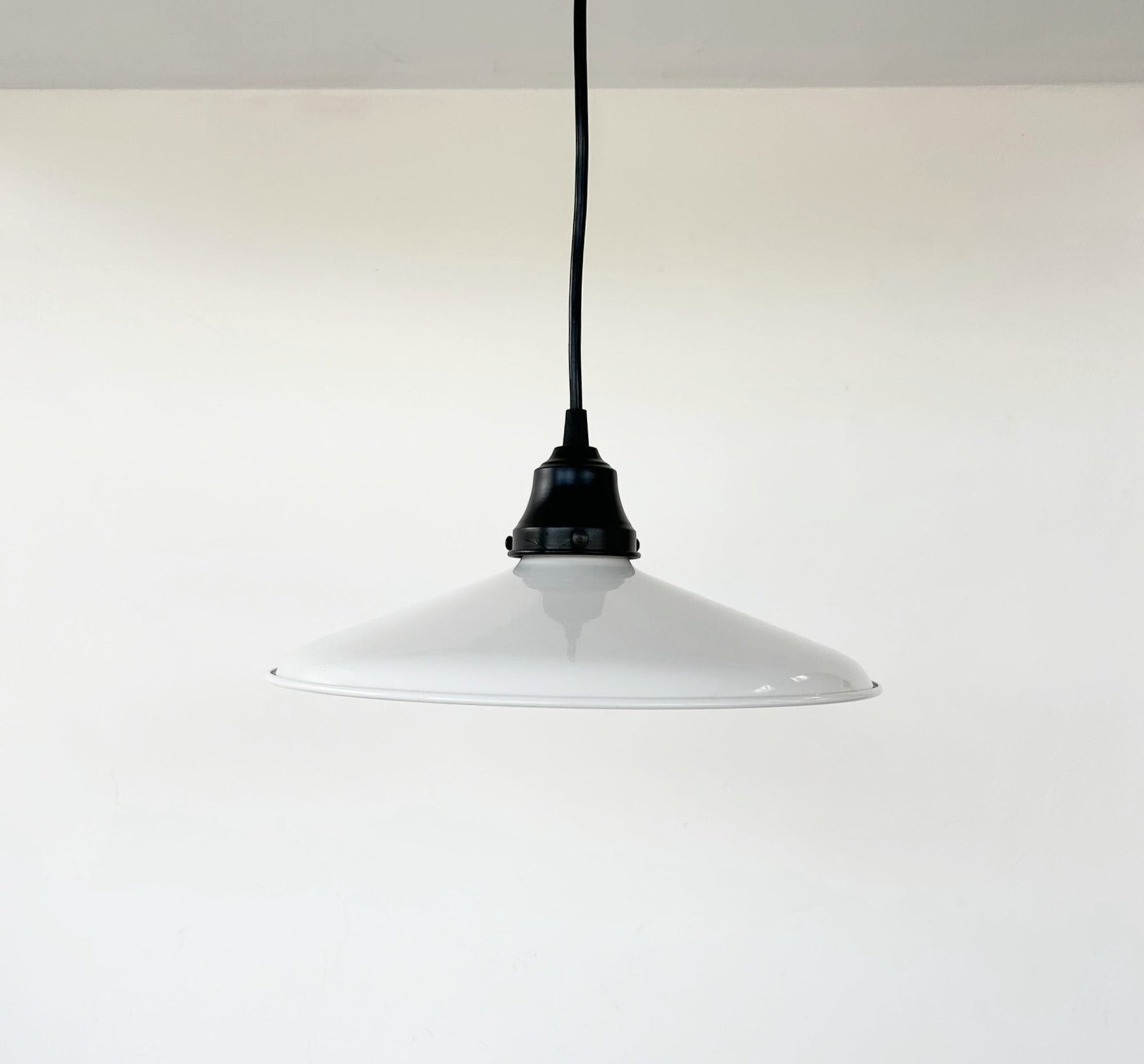 White pendant light with black cord on a white background