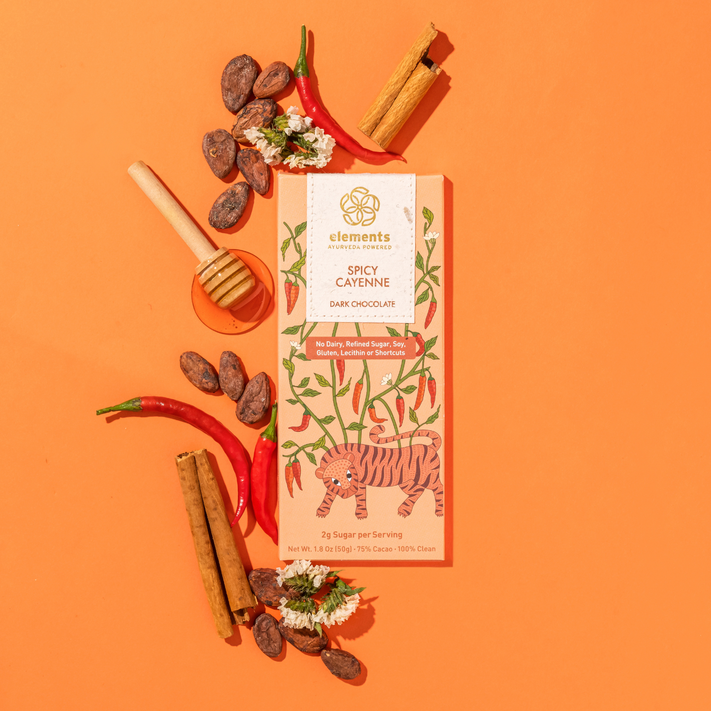 Spicy cayenne dark chocolate bar with ingredients on an orange background