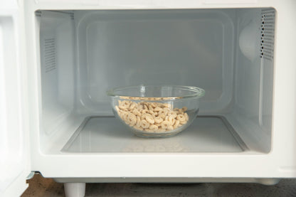 Glass bowl with cashews inside a microwave oven