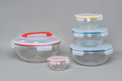 Set of glass food storage containers with colorful lids on a gray background
