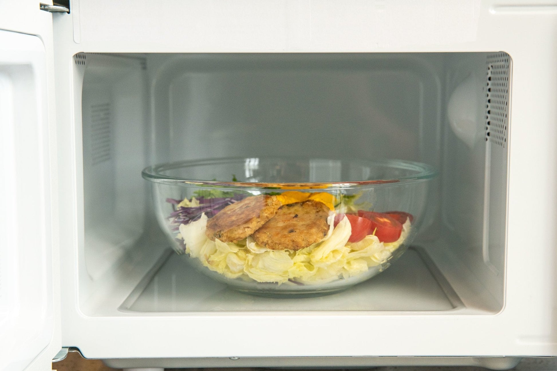 Glass bowl with food inside a microwave oven