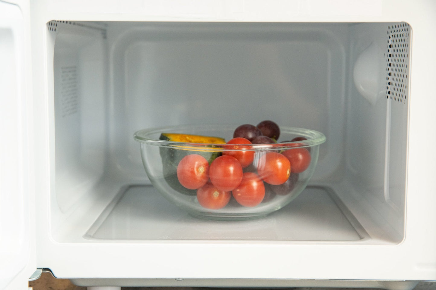 Glass bowl with fruits inside a microwave oven